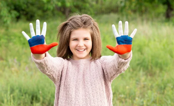 Niña mostrar las manos pintadas en Rusia colores de la bandera caminando al aire libre. Día de la bandera rusa. Patriotas ciudadanos nacionalidad. 12 de junio. 22 de agosto vacaciones. 4 de noviembre —  Fotos de Stock