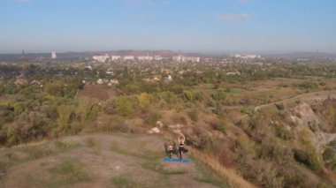 Yavru kızıyla birlikte sabahları göl kenarındaki yüksek tepelerde yoga egzersizleri yapan narin bir annenin hava yörüngesindeki çekimi şehrin hareketli bölgelerinden uzakta, iyi örnek teşkil eder ve sağlıklı alışkanlıklarını aşılar.