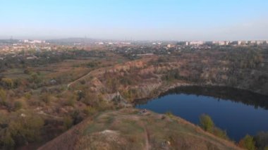 İnce ve genç annenin hava drone görüntüsü, sabahları kızıyla birlikte yüksek tepelerde, göl kenarında yoga egzersizleri yapıyor. Şehrin çalkantısından uzakta, iyi örnek oluyor ve sağlıklı alışkanlıklarını ona aşılıyor.