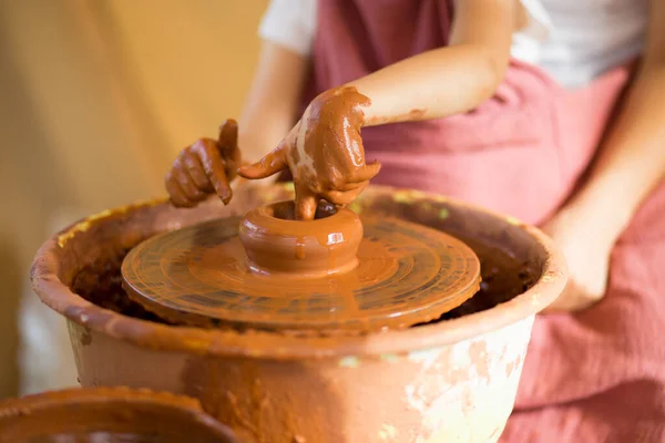 Master class pour enfant. Les mains de l'enseignant montrent aux enfants comment faire des plats en céramique sur la roue du potier. Artiste travaille avec de l'argile. Petite fille sculpter tasse argile — Photo