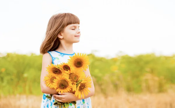 Outdoor-Porträt von entzückenden kleinen Mädchen in blauem Kleid geht in einem Feld von Sonnenblumen, sammeln und sammeln Strauß. Sommerferien — Stockfoto