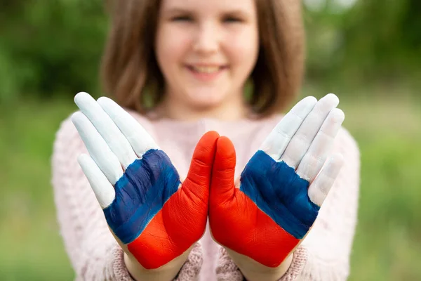 Niña mostrar las manos pintadas en Rusia colores de la bandera caminando al aire libre, centrarse en las manos. Día de la bandera rusa. Patriotas ciudadanos nacionalidad. 12 de junio. 22 de agosto vacaciones. 4 de noviembre — Foto de Stock