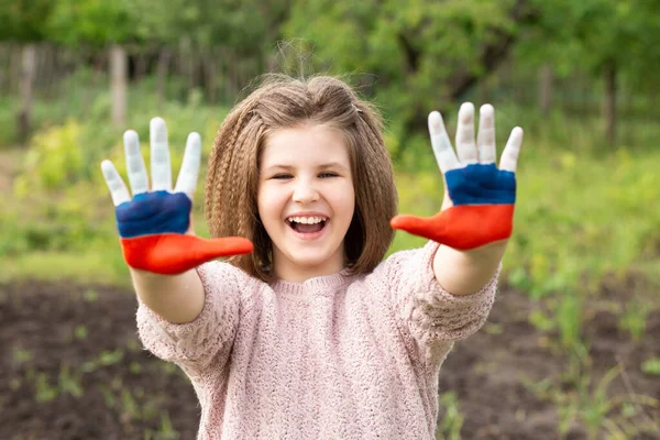 Niña mostrar las manos pintadas en Rusia colores de la bandera caminando al aire libre. Día de la bandera rusa. Patriotas ciudadanos nacionalidad. 12 de junio. 22 de agosto vacaciones. 4 de noviembre —  Fotos de Stock