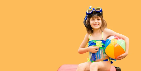 Grappig klein kind in snorkelmasker en wetsuit voor onderwater duiken zit op rode koffer geïsoleerd op gele zomerachtergrond. Familie reizen levensstijl in de zomer avonturenkamp. Zwemkind — Stockfoto