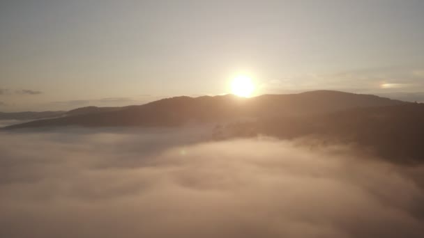 Vista aérea do drone superior acima das nuvens e do céu na hora maravilhosa do nascer do sol da manhã. Voando através das nuvens acima dos cumes das montanhas. Belo pôr do sol cume da montanha — Vídeo de Stock