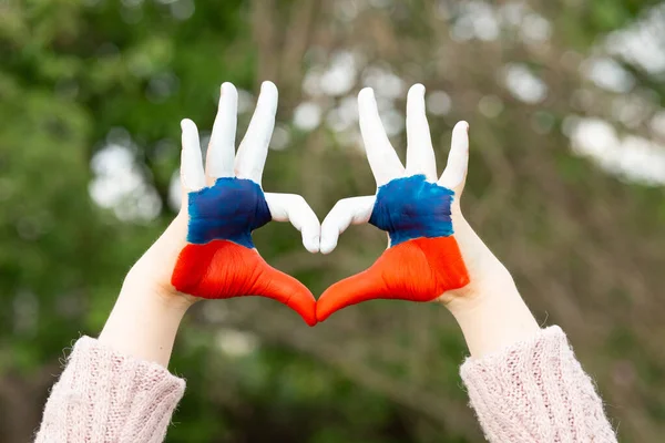 Le mani dei bambini dipinte a colori con bandiera russa mostrano il simbolo del gesto del cuore e dell'amore. A forma di cuore di bambini dipinti a mano in bianco blu colore rosso, i bambini amano il concetto. Fotografia Stock