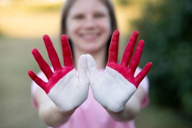 Çocuk kız elleri Endonezya bayrağı renginde boyalı, ellerine odaklan. Endonezya vatanseverliği kavramı. Endonezya Bağımsızlık Günü, 17 Ağustos