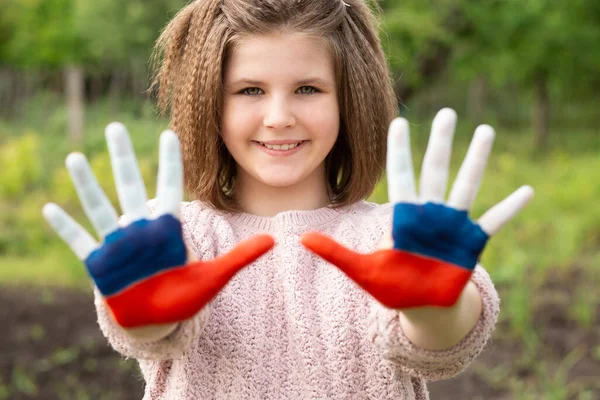 Παιδί κορίτσι δείχνουν τα χέρια ζωγραφισμένα στη Ρωσία χρώματα σημαία με τα πόδια εξωτερική. Ημέρα της ρωσικής σημαίας. Πατριώτες πολίτες εθνικότητας. 12 Ιουνίου. 22 Αυγούστου διακοπές. 4 Νοεμβρίου — Φωτογραφία Αρχείου