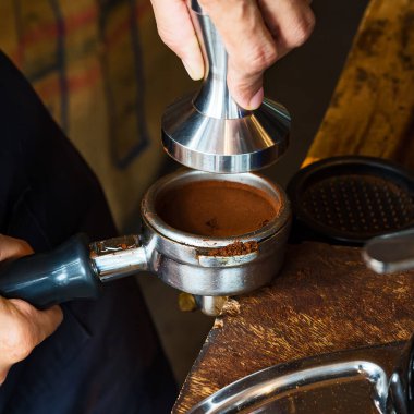 Barista kahve yapmak için kahve ve portafilter tutuyor. Kahve yapma konsepti.