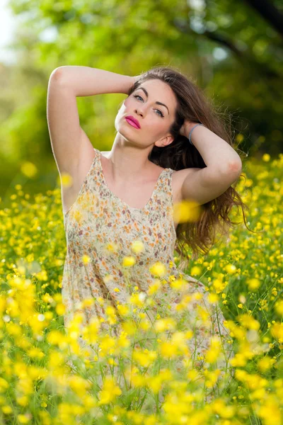 Beautiful young girl among yellow flowers — Stock Photo, Image