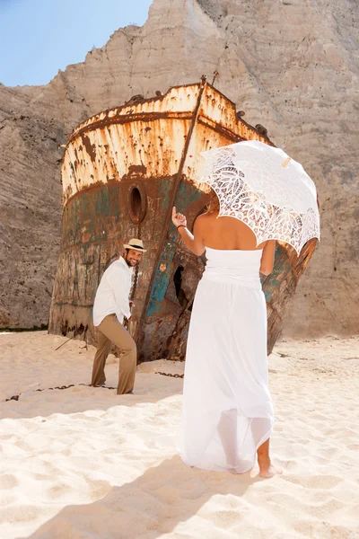 Pareja joven en una playa con naufragio — Foto de Stock