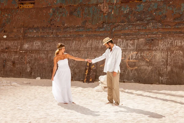 Pareja joven en una playa con naufragio —  Fotos de Stock