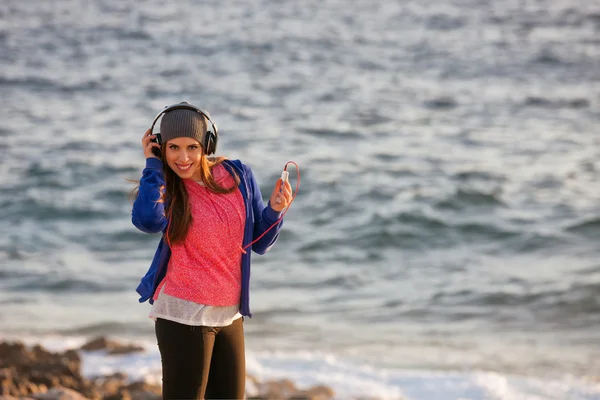 Chica joven con auriculares en la playa — Foto de Stock