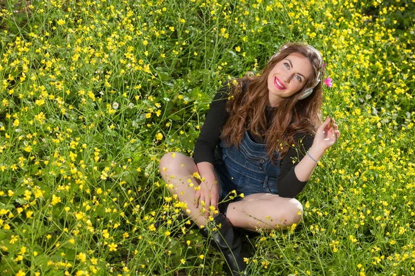 Menina bonita com fones de ouvido nas flores — Fotografia de Stock