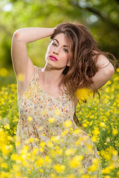 Hermosa joven entre flores amarillas — Foto de Stock