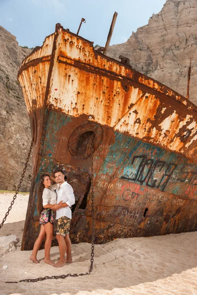 Young couple in a beach with shipwreck — Stock Photo, Image