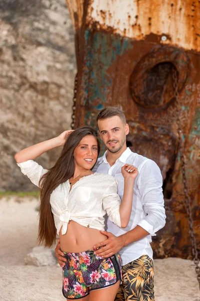 Young couple in a beach with shipwreck — Stock Photo, Image