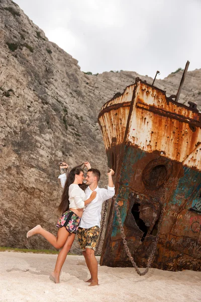 Giovane coppia in spiaggia con naufragio — Foto Stock