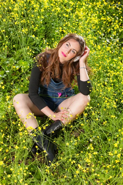 Hermosa joven con auriculares en las flores — Foto de Stock