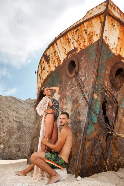 Giovane coppia in spiaggia con naufragio — Foto Stock