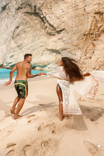 Young couple in a beach with shipwreck — Stock Photo, Image