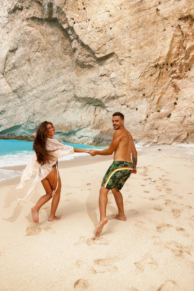 Jovem casal em uma praia com naufrágio — Fotografia de Stock