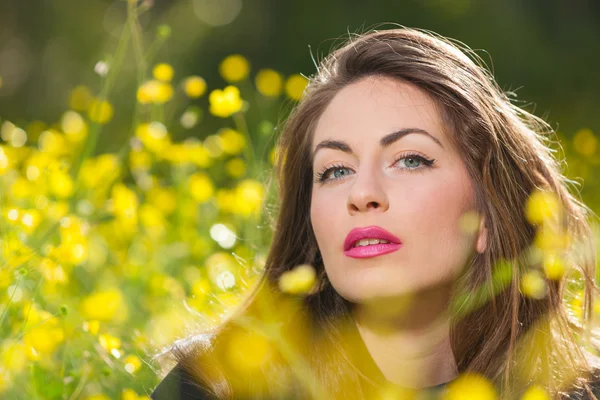 Hermosa joven entre flores amarillas — Foto de Stock