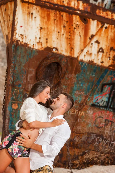 Young couple in a beach with shipwreck — Stock Photo, Image