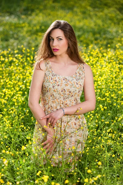 Hermosa joven entre flores amarillas — Foto de Stock