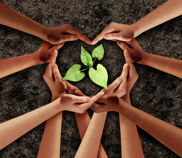 Earth day love and agriculture support or ecology unity as heart hands in a group of people connected together shaped as a supporting symbol helping protect a seedling expressing the feeling of teamwork and togetherness.