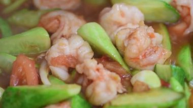 Tatlı ve ekşi domates sosunda kaynayan karides ve salatalık.