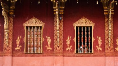 Luang Prabang 'daki bir tapınak duvarı ve penceresi kırmızı ve altın renklerle boyanmış.