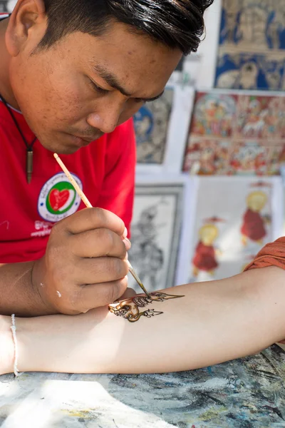 Artist drawing freehand on a customer's — Stock Photo, Image