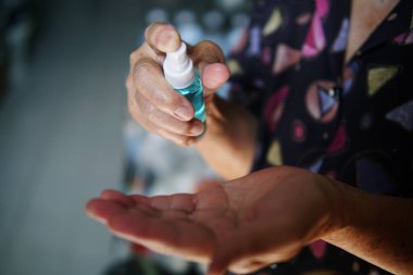 Alkol spreyi şişeli yaşlı kadının eli..