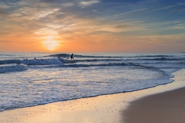 Pratik sörfçü günbatımında sörf.