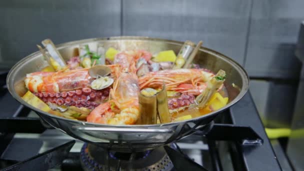 O chef polvilha verduras com uma cataplan com polvo, frutos do mar e legumes. Vídeo horizontal. Close-up. — Vídeo de Stock