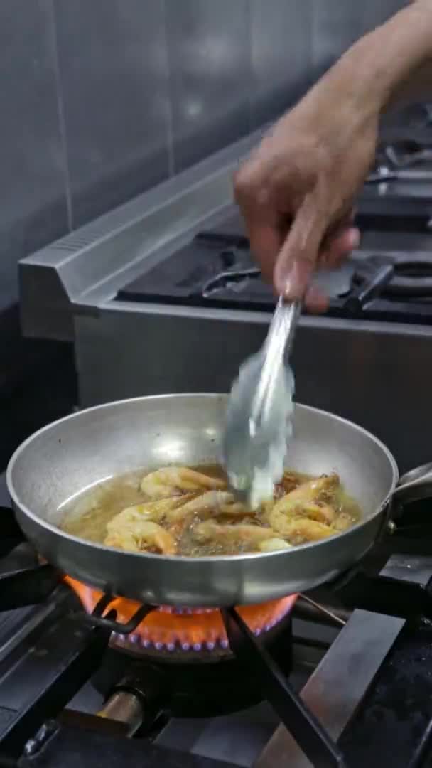 Bucătarul prăjește și întoarce creveții, calmarii, fructele de mare la căldură ridicată. Video vertical. Close-up . — Videoclip de stoc
