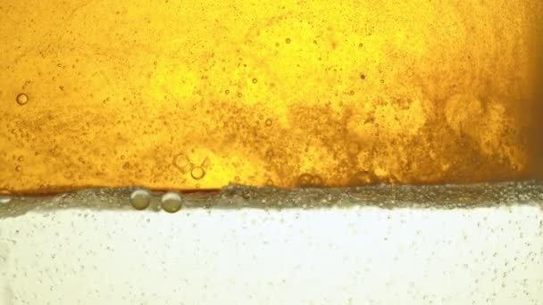 Καύσιμο, λάδι του κίτρινου, χρυσό χρώμα χύνεται σε ένα γυάλινο δοχείο στο εργαστήριο διανέμοντας μικρές ήρεμες φυσαλίδες. — Αρχείο Βίντεο