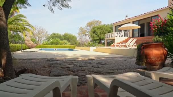 Luksusowy widok z okna na basen z bujanym krzesłem i ogrodem palm. — Wideo stockowe