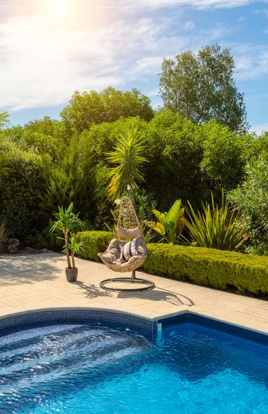 Luxuriöser Pool im Garten einer Privatvilla, Hängesessel mit Kissen für Freizeittouristen, im Sommer. Portugal, Algarve. — Stockfoto