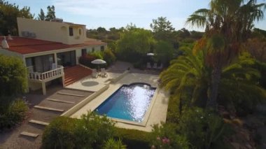 Havuzu ve farklı ağaçlara sahip bahçeli lüks bir ev. Güneşlenmek için iki yatak