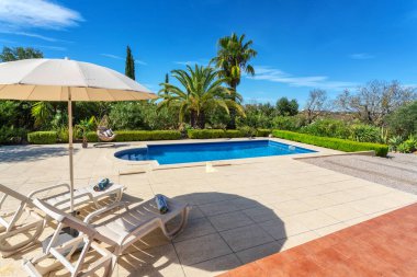Özel bir villanın bahçesinde lüks bir havuz, tatil turistleri için yastıklı sallanan sandalye. Portekiz, Algarve.