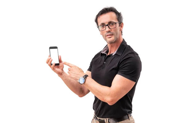 Mężczyzna w średnim wieku wskazuje na smartfona. Portret atrakcyjnego mężczyzny w okularach. echnologia, gadżet, koncepcja reklamy — Zdjęcie stockowe