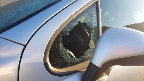 El ladrón rompió la ventana lateral del coche para robar. Un ejemplo de seguro contra robo. — Foto de Stock