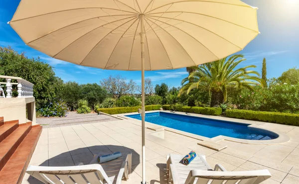 Lyxig pool i trädgården i en privat villa, hängande stol med kuddar för fritidsturister, på sommaren. Portugal, Algarve. — Stockfoto