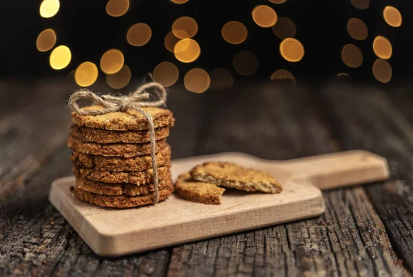 Una pila di biscotti biologici di farina d'avena per Natale, con luci incandescenti bokeh. Primo piano. — Foto Stock