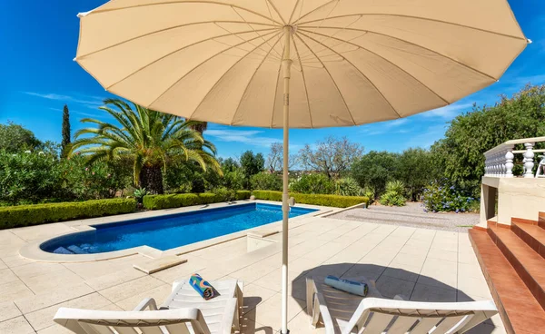 Luxuriöser Pool im Garten einer Privatvilla, Hängesessel mit Kissen für Freizeittouristen, im Sommer. Portugal, Algarve. — Stockfoto