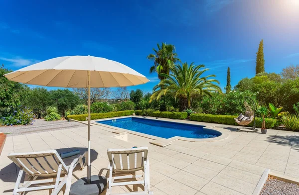 Lujosa piscina en el jardín de una villa privada, silla colgante con almohadas para turistas de ocio, en verano. Portugal, Algarve. — Foto de Stock