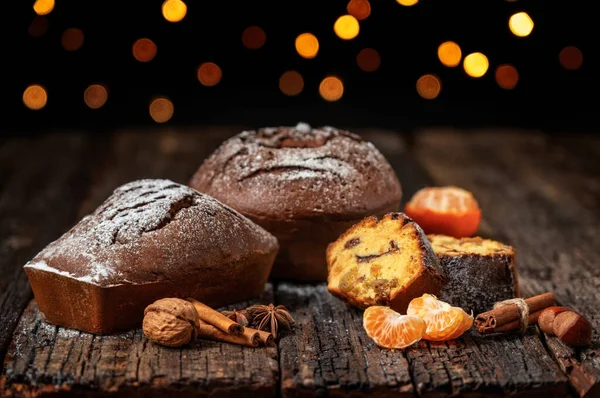 Tres panes de Navidad, estolados, con mandarina, sobre una mesa de madera texturizada, sobre el fondo de luces borrosas en bokeh. En Navidad. — Foto de Stock