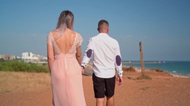 Genç bir çift romantik bir toplantıda deniz kenarında yürür. Balayı. Sevgililer Günü.